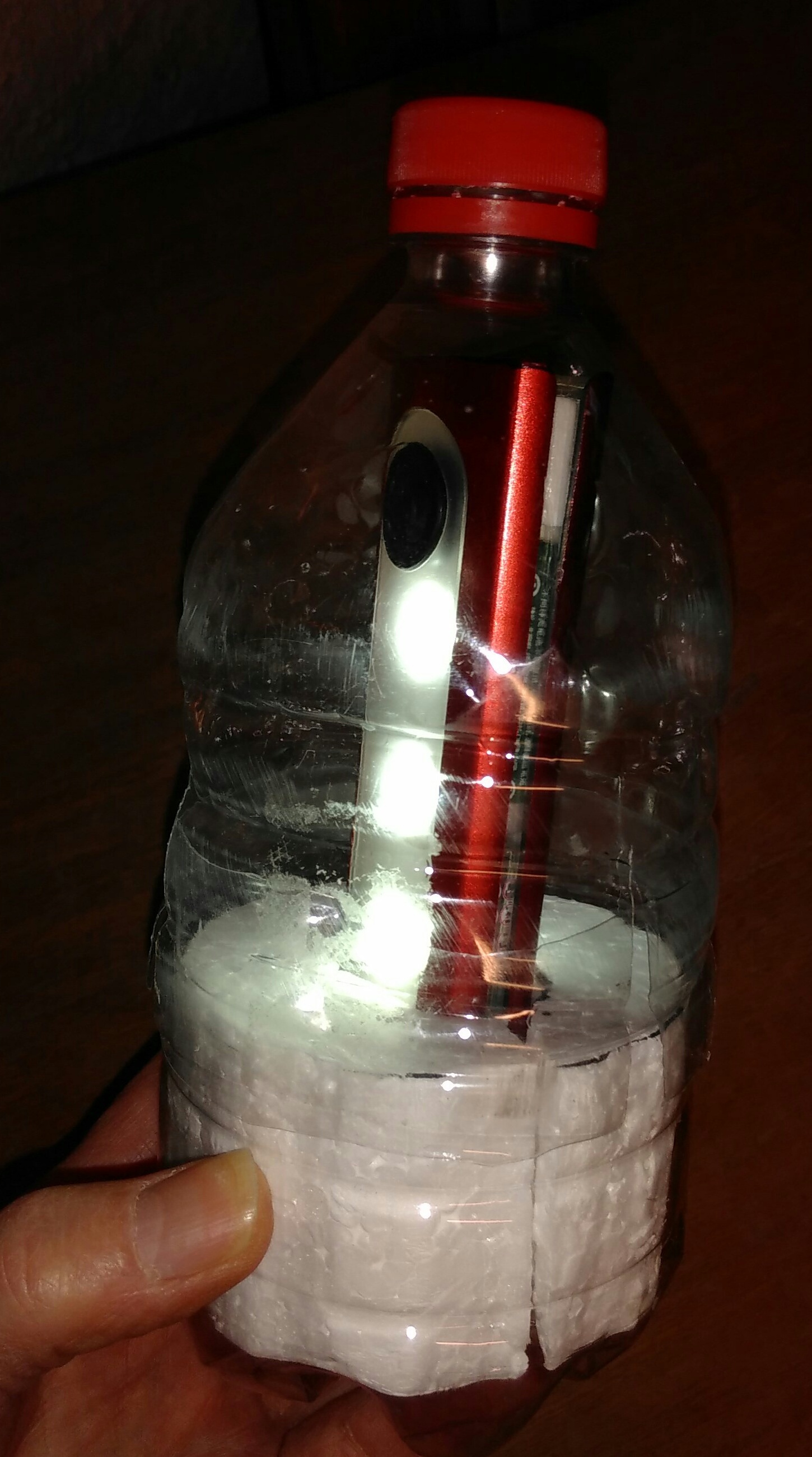 Klarsicht-Flasche mit roten Deckel und rundum leutender LED-Taschenlampe innen drin